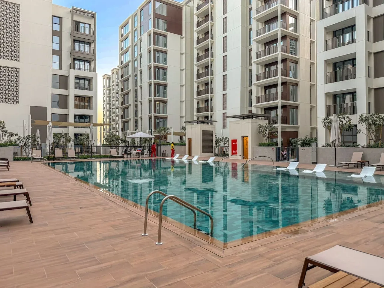 Una piscina está en un patio rodeado de edificios de apartamentos modernos.