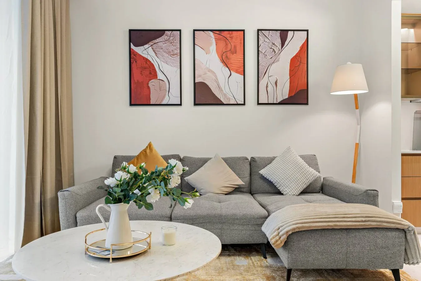 Una sala de estar con asientos grises, una mesa de centro redonda y arte abstracto en la pared.