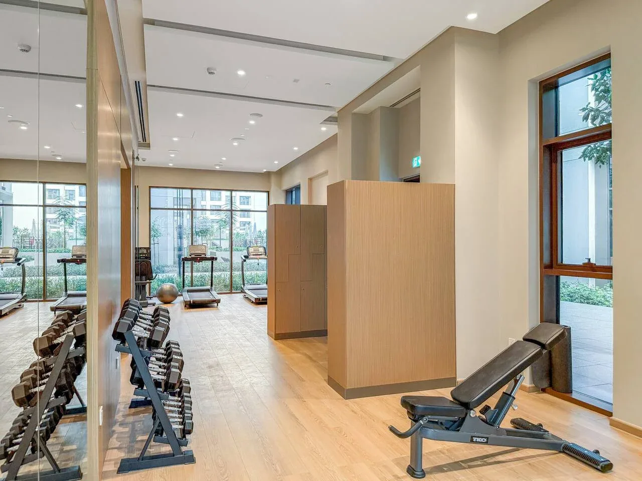 Un gimnasio luminoso con equipos de ejercicio y grandes ventanas.