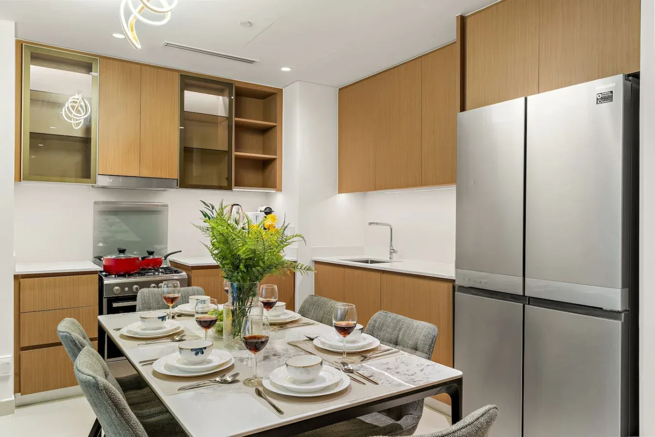 Una mesa está puesta en una cocina con gabinetes de madera y un refrigerador grande.