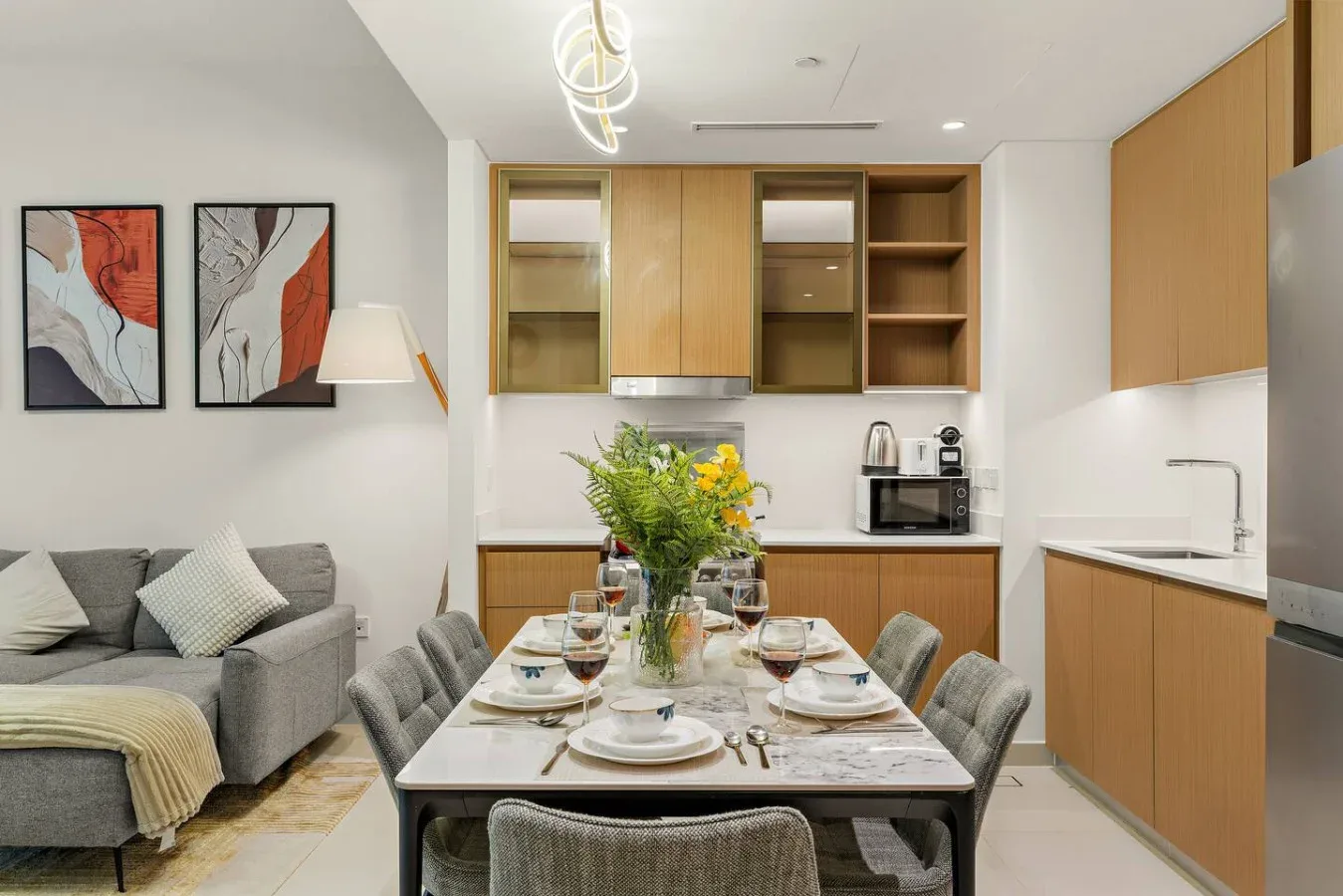 Un comedor con la mesa puesta está junto a una sala de estar y una cocina compacta.