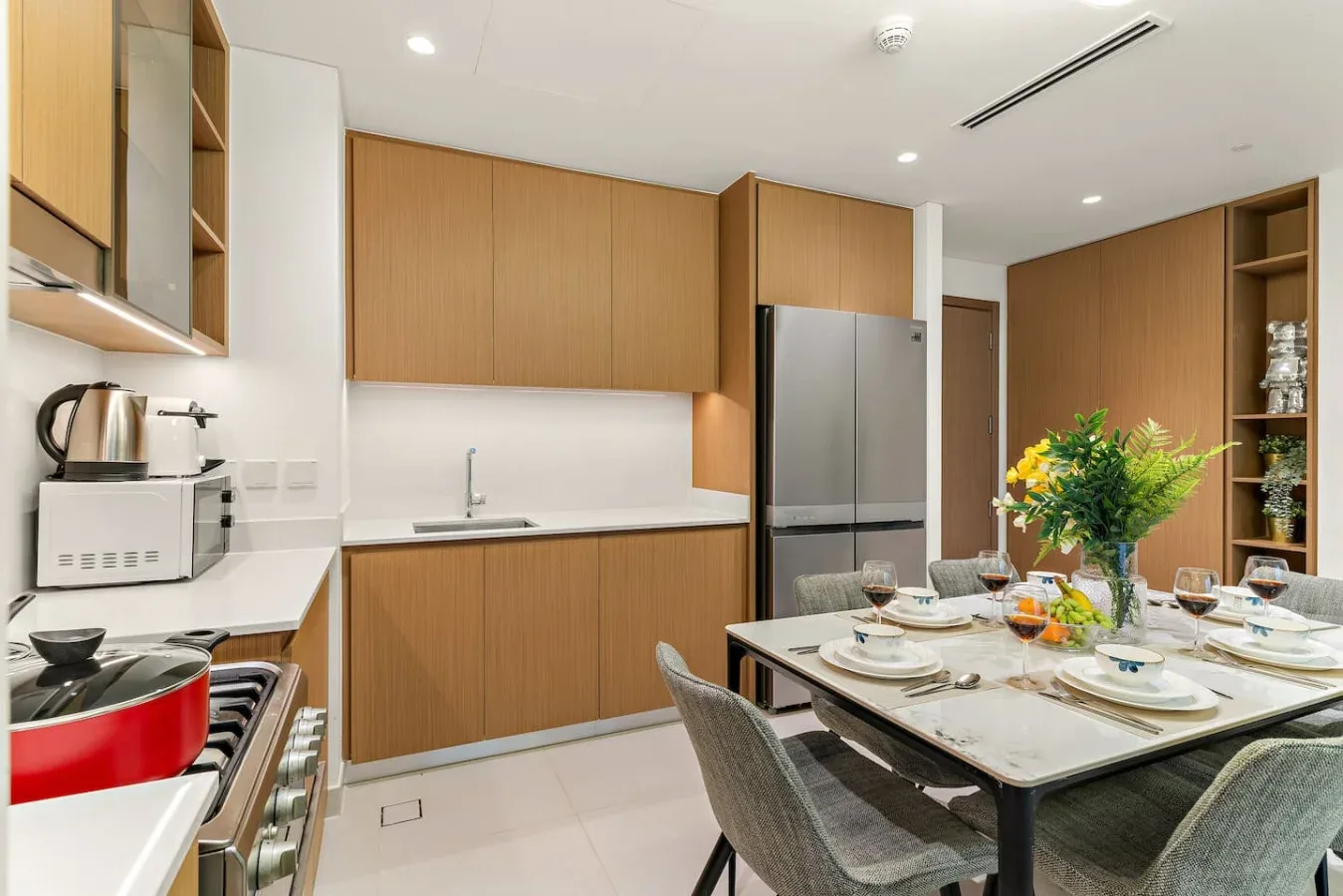 Cocina y comedor modernos con gabinetes de madera y una mesa preparada para comer.