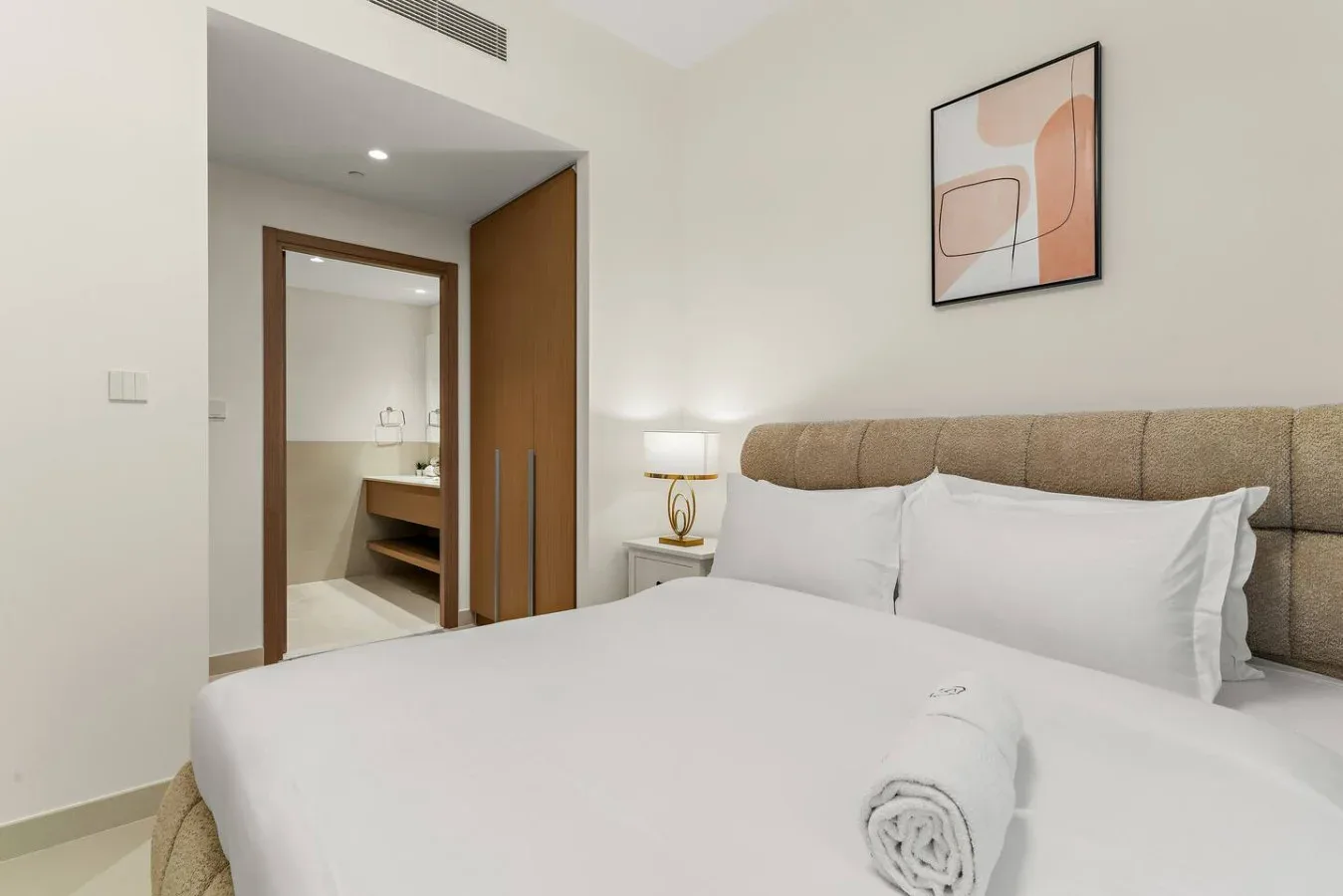 Un dormitorio con una cama tendida y una entrada al baño.