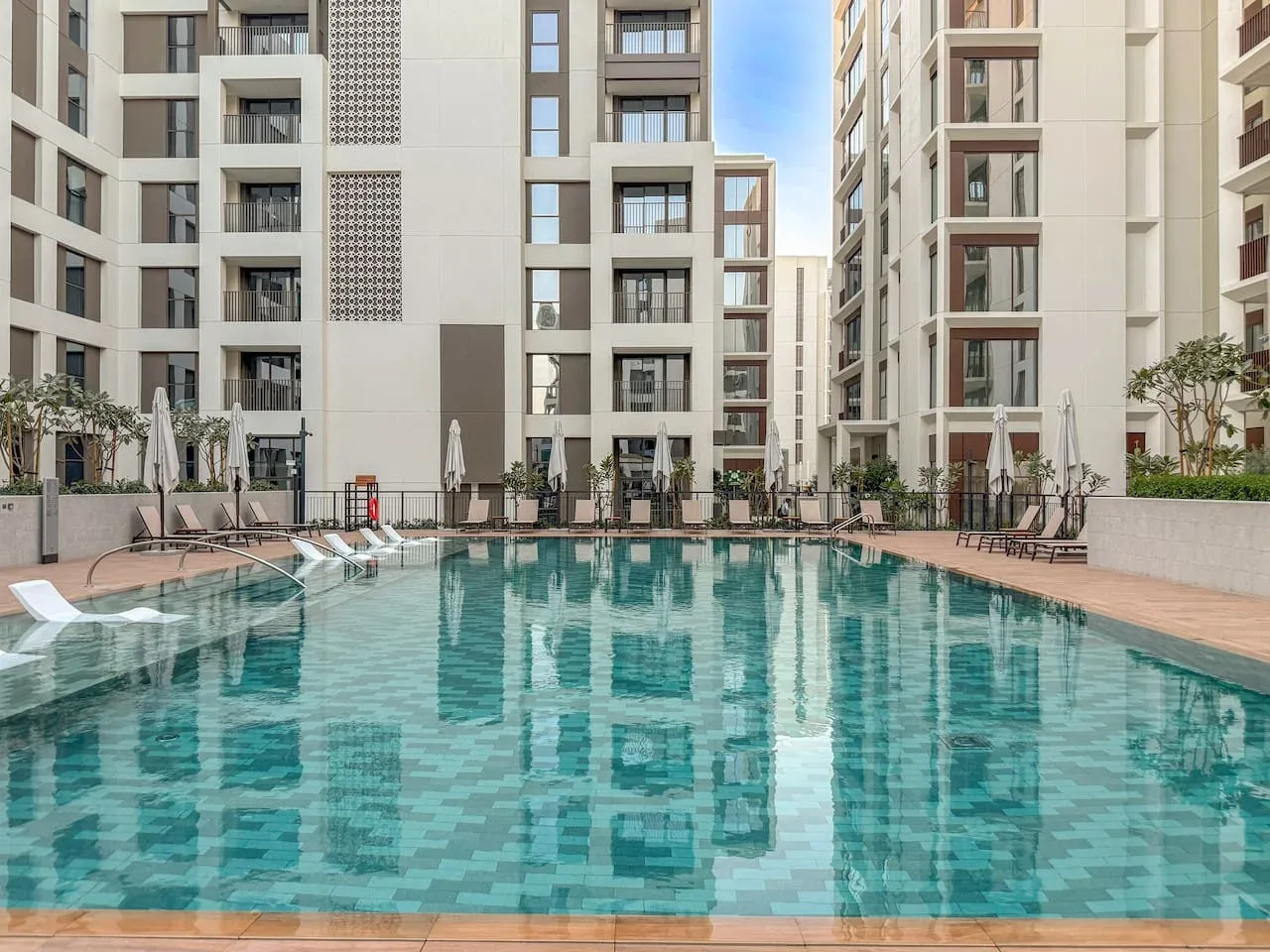 Una piscina al aire libre está rodeada de edificios de apartamentos altos.