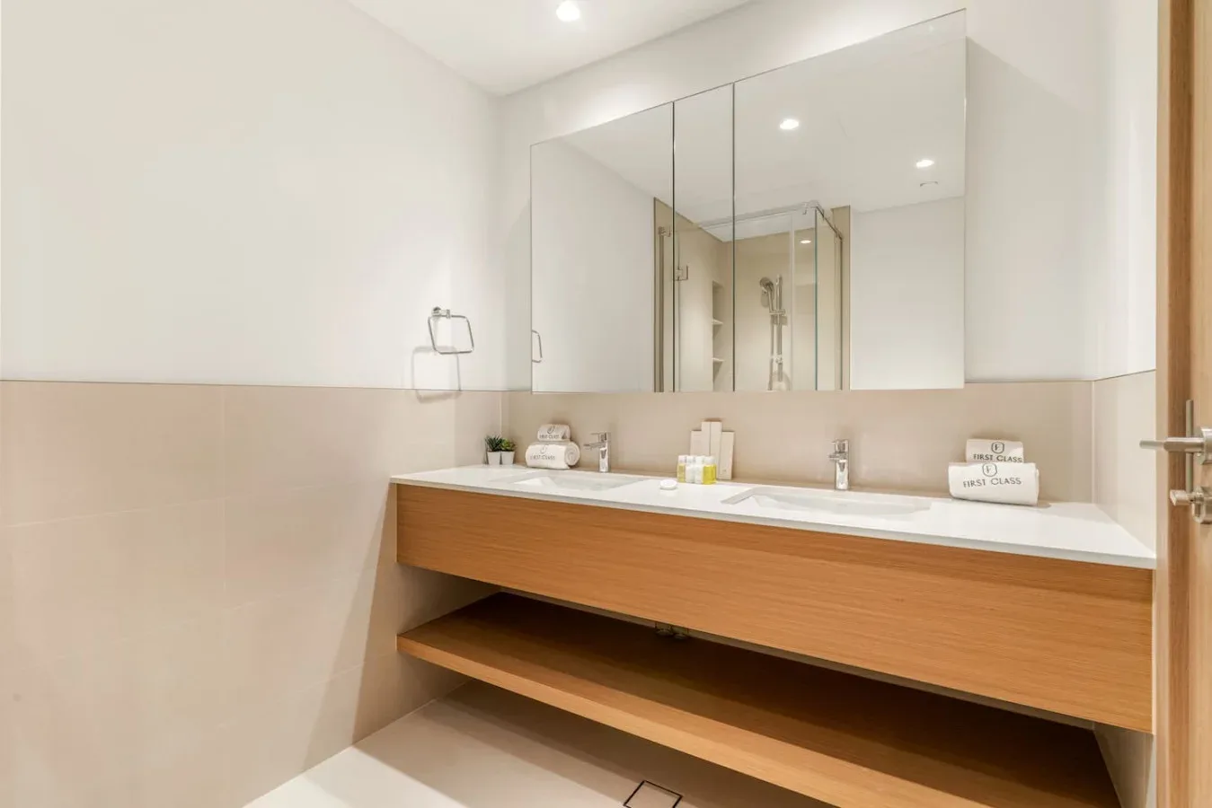 Un baño luminoso con un largo tocador bajo un gran espejo.