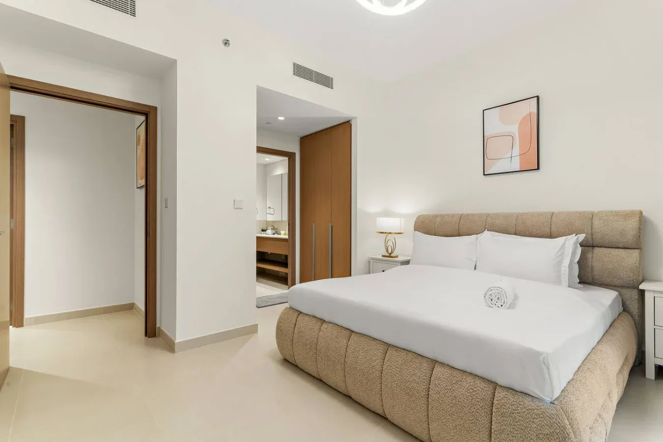 Un dormitorio con una cama grande, una mesita de noche y un cuadro en la pared.