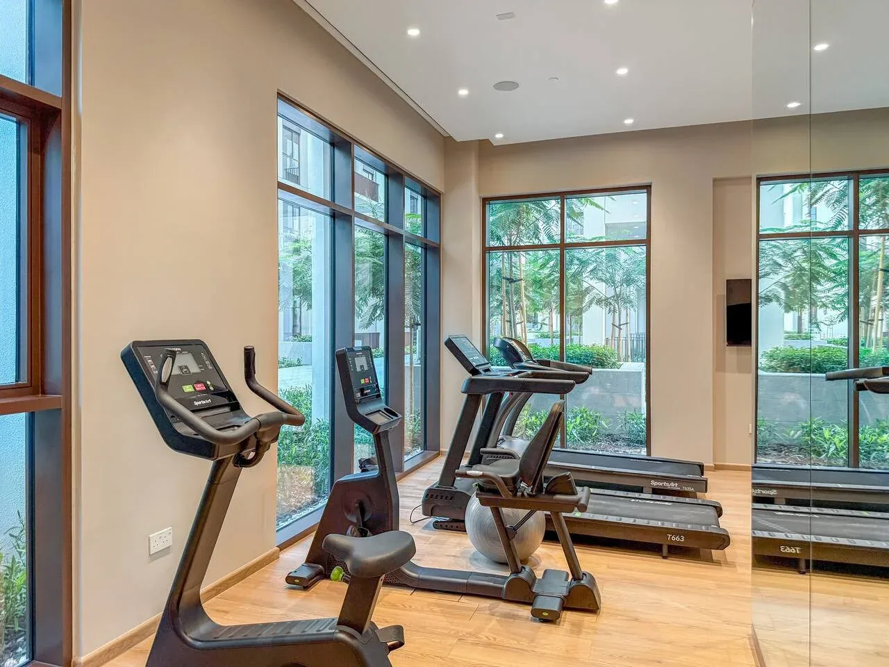 Un gimnasio con máquinas de ejercicio junto a grandes ventanales.