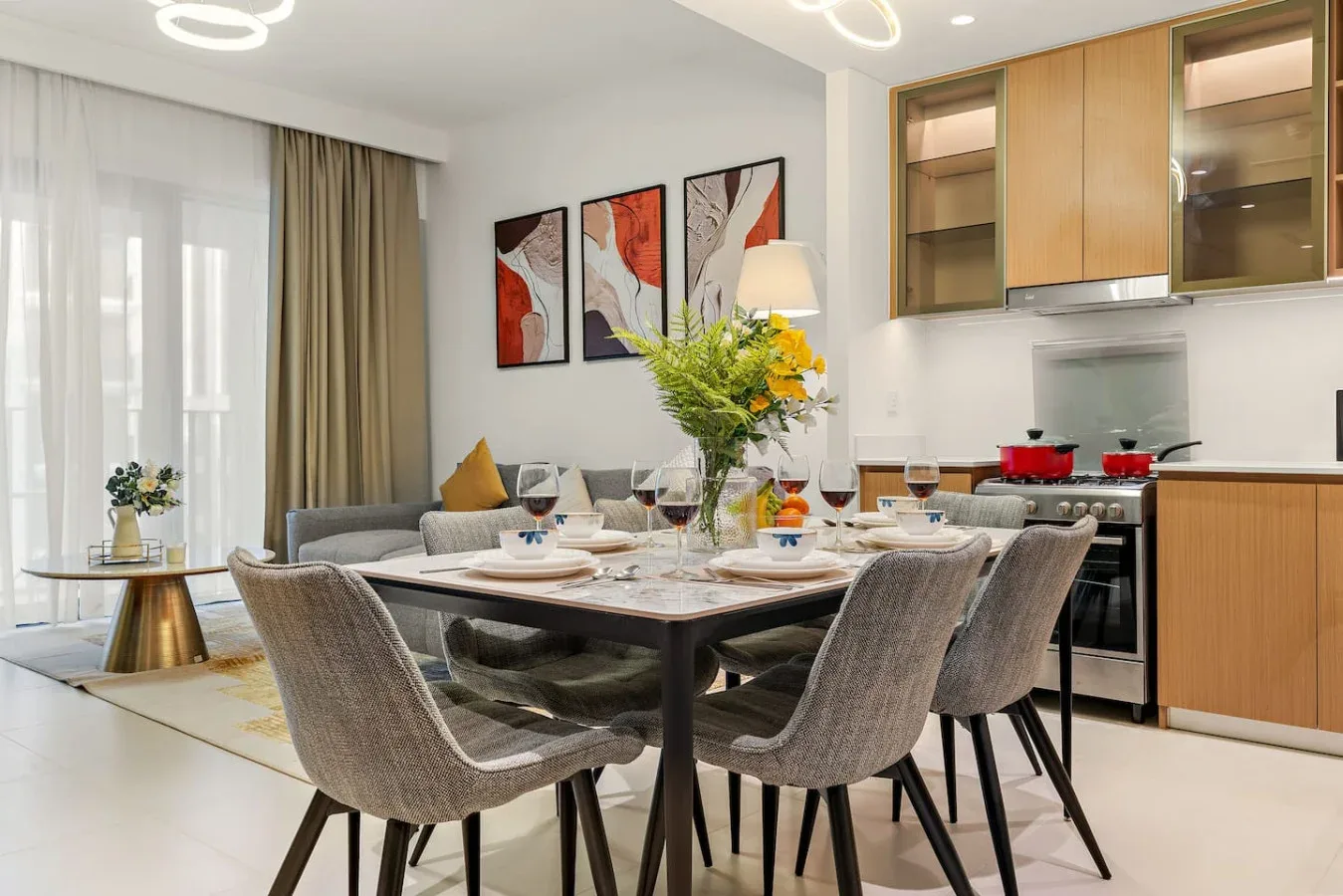 Comedor con la mesa puesta y una zona de estar junto a grandes ventanales.