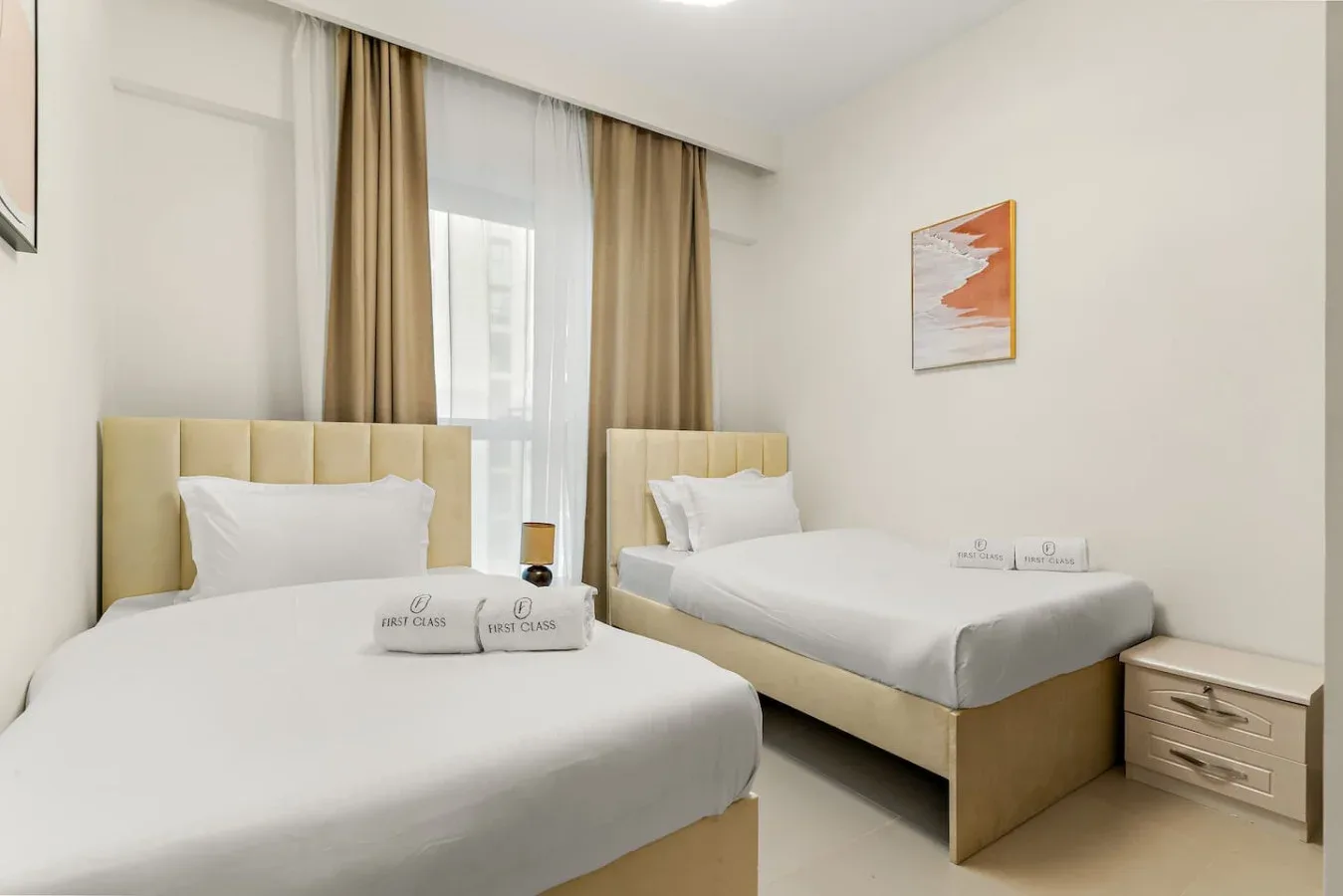 Un dormitorio con dos camas, ropa de cama blanca y cortinas junto a la ventana.
