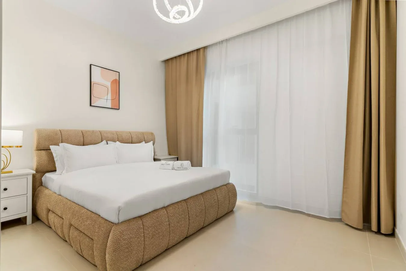 Un dormitorio con una cama grande junto a una ventana con cortinas translúcidas.