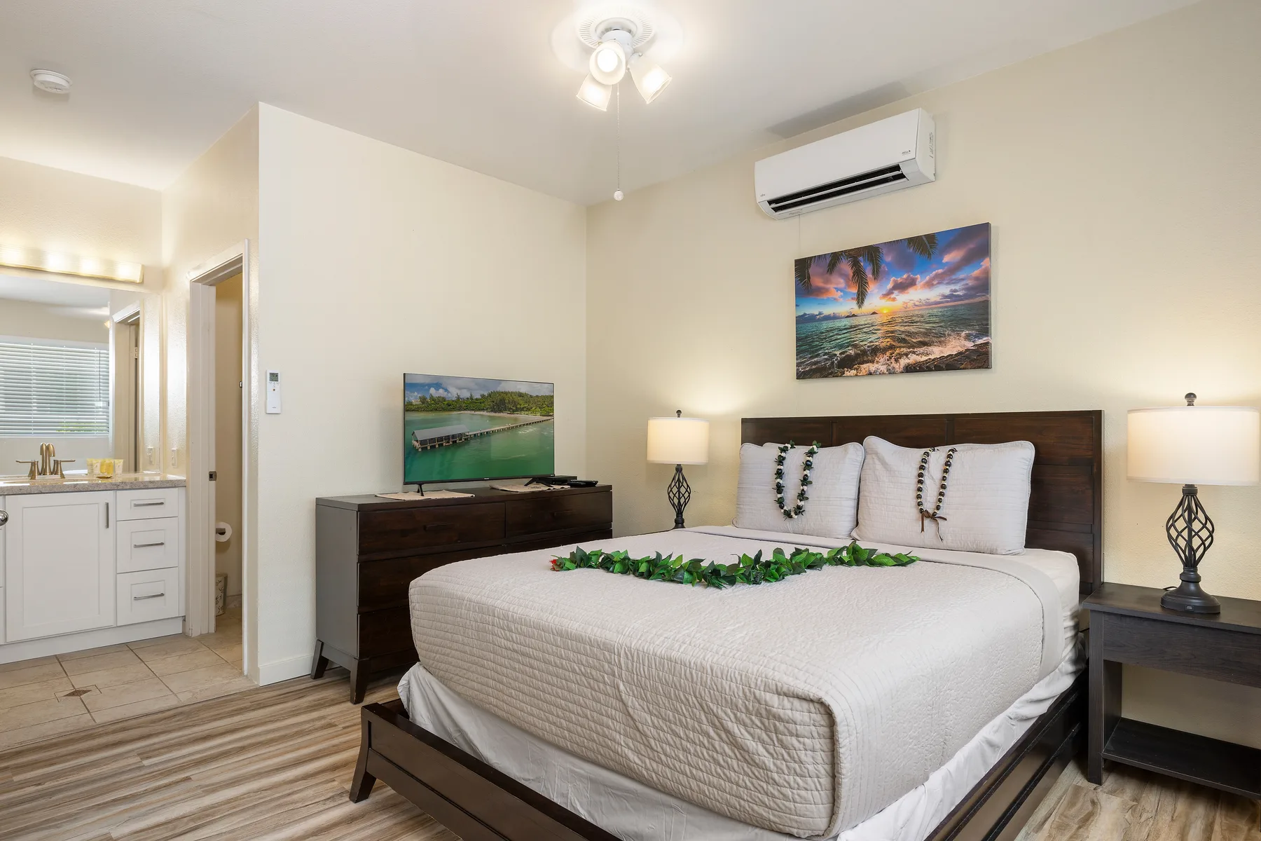 Un dormitorio con una cama bien tendida, mesitas de noche y un televisor montado en la pared.