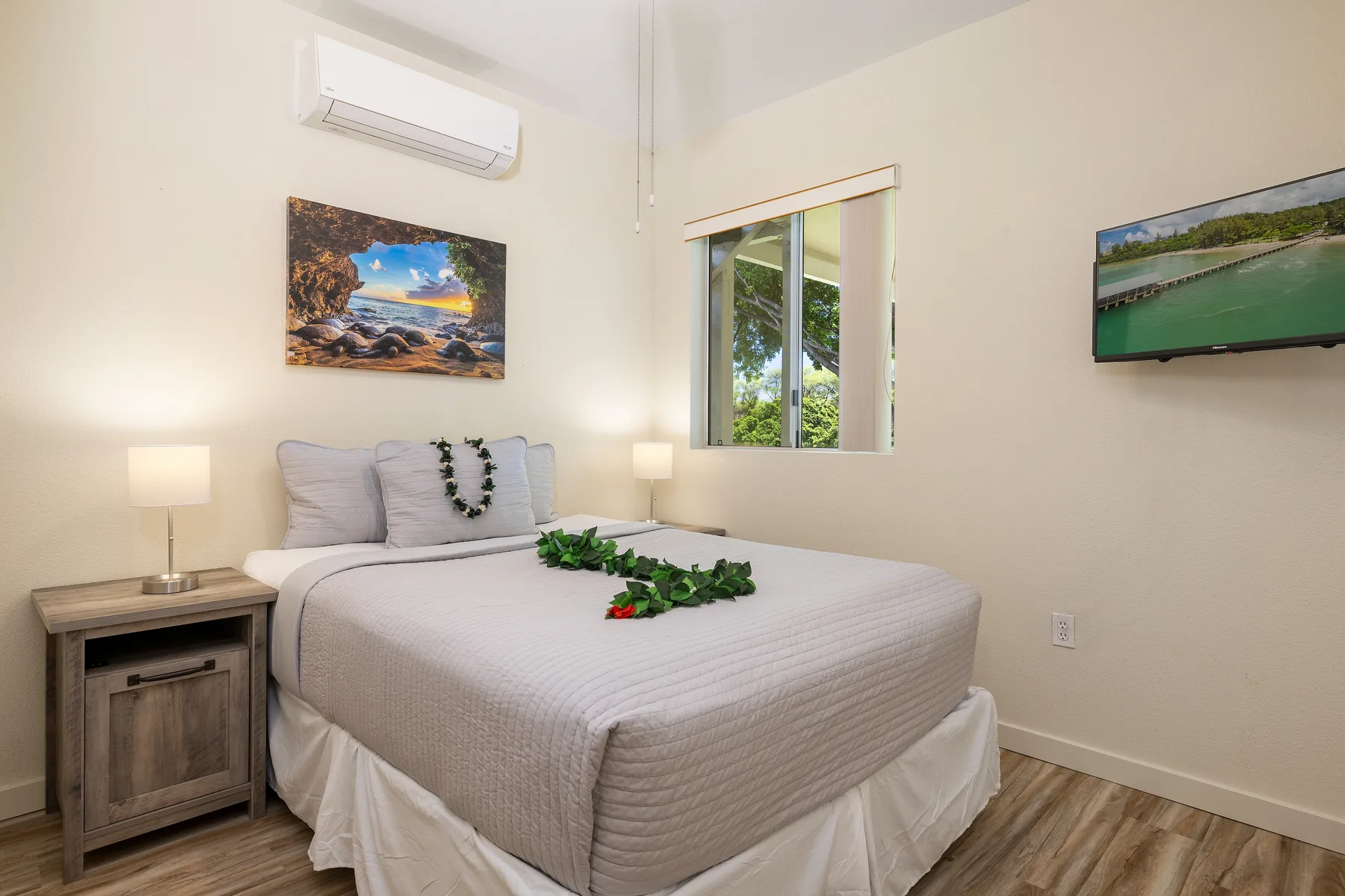 Un dormitorio con una cama bien tendida, una mesita de noche y un televisor de pared.
