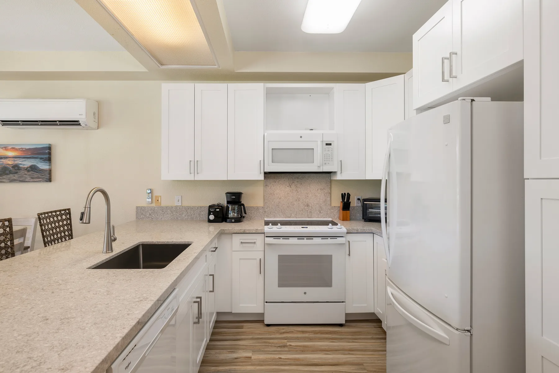 Una cocina luminosa con gabinetes blancos, encimera y electrodomésticos de acero inoxidable.