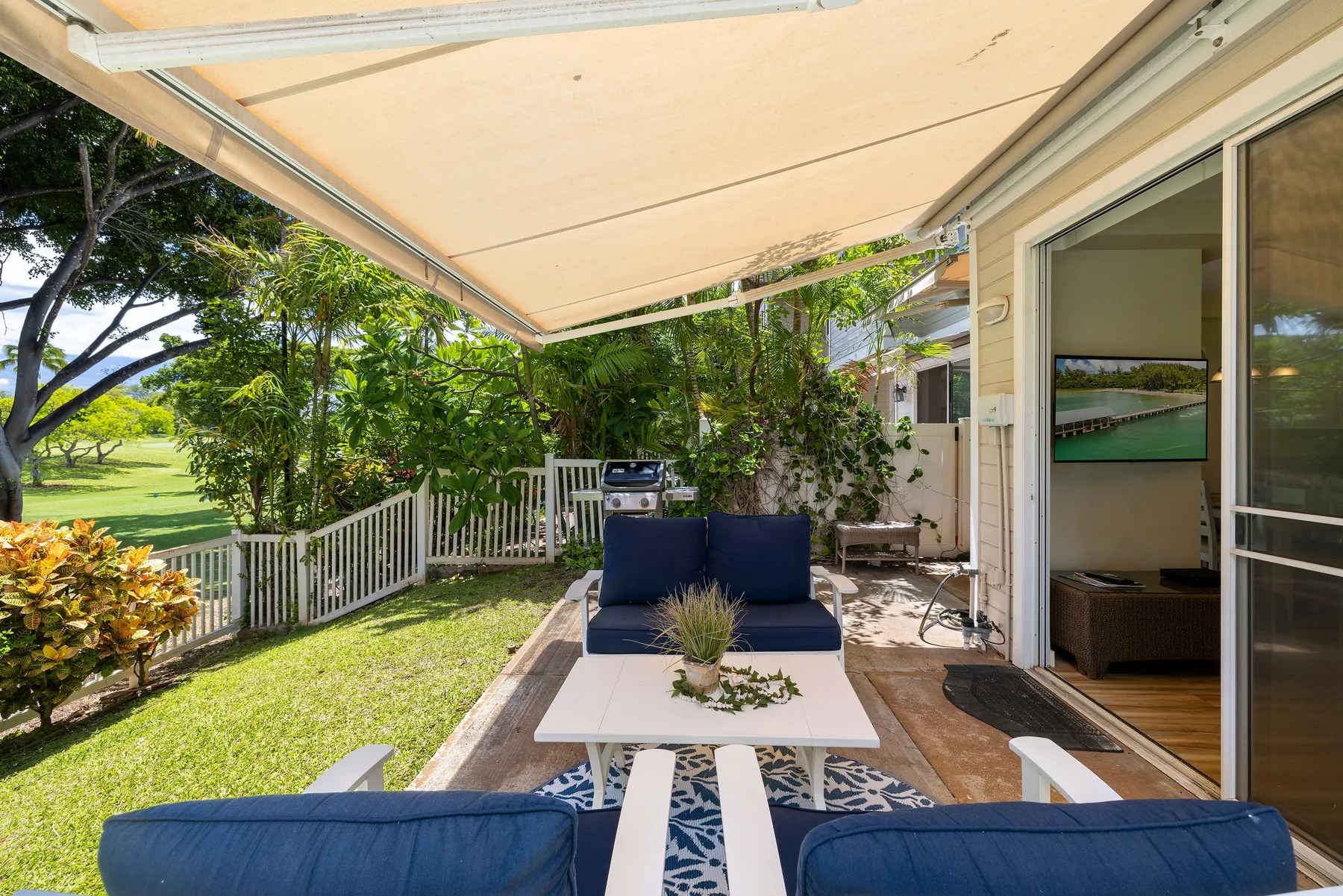 Un patio al aire libre con asientos acolchados y una mesa bajo un toldo retráctil.