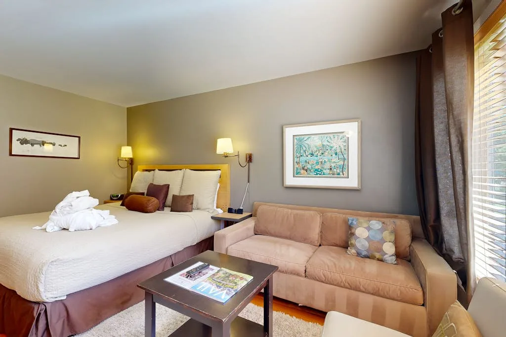 A bedroom with a bed and a sofa beside the window.