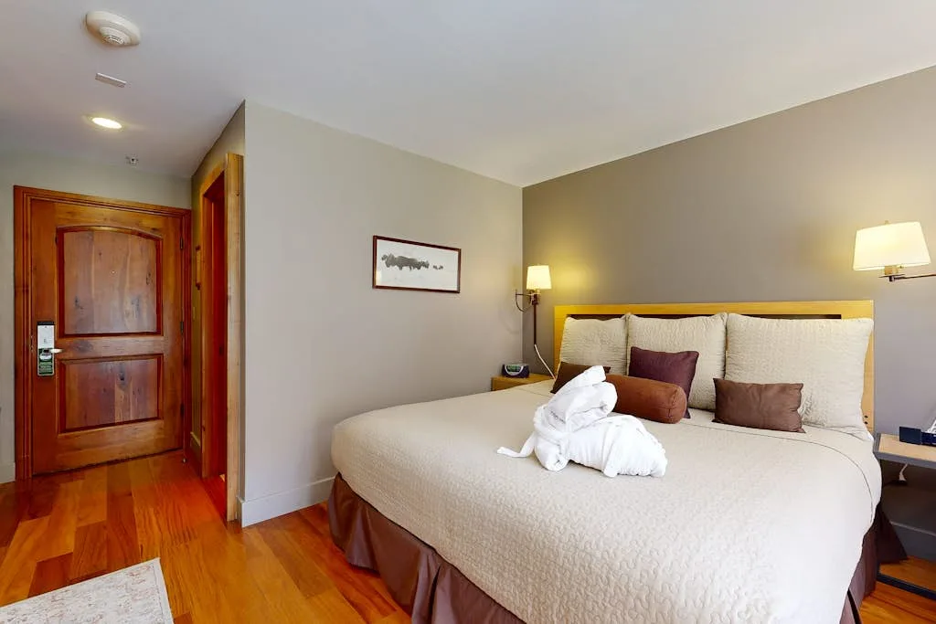 Un dormitorio con una cama bien tendida y un cuadro en la pared.