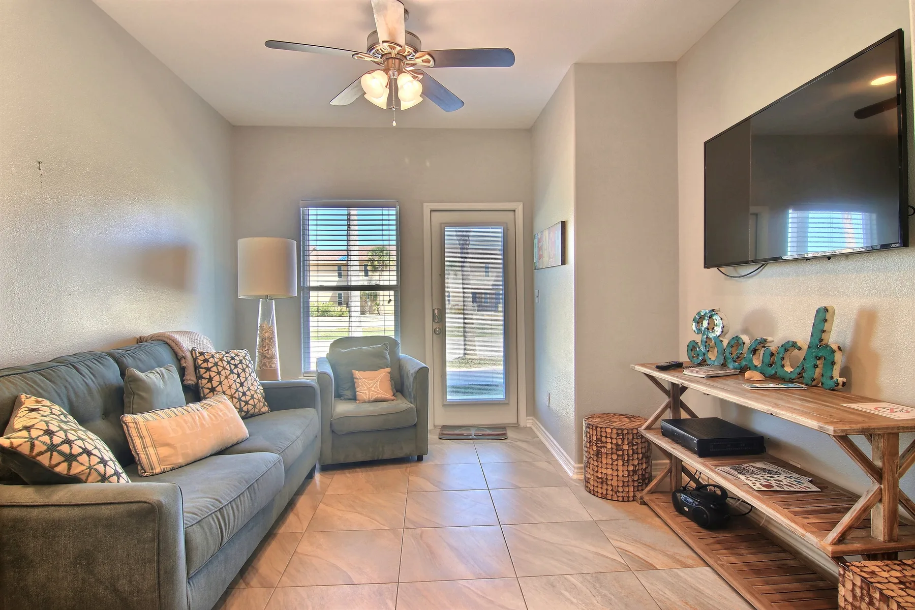 A living room with seating, a television, and a ceiling fan.