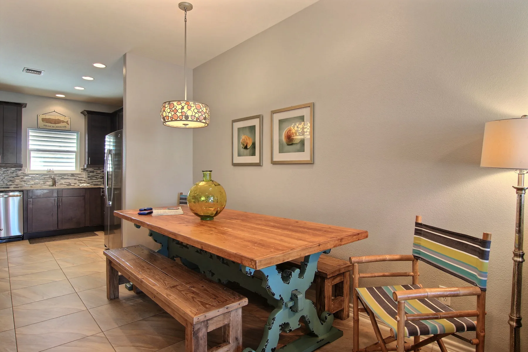 A dining area with a wooden table, bench, and striped chairs.