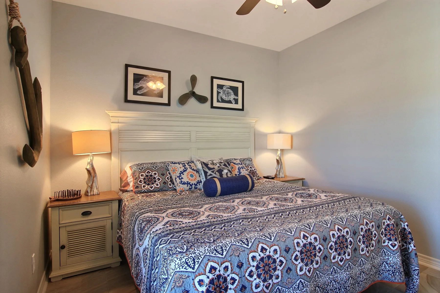 A bedroom with a patterned bedspread, bedside tables, and matching lamps.