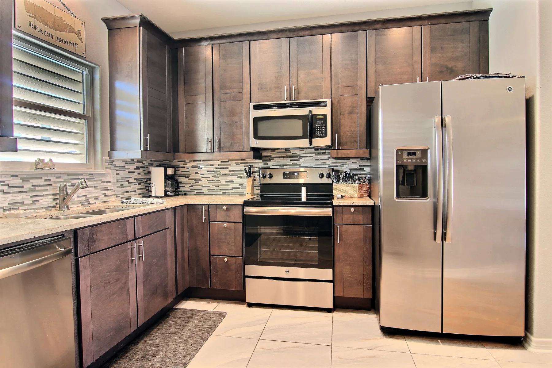 A kitchen with dark cabinets, stainless steel appliances, and a tiled backsplash.