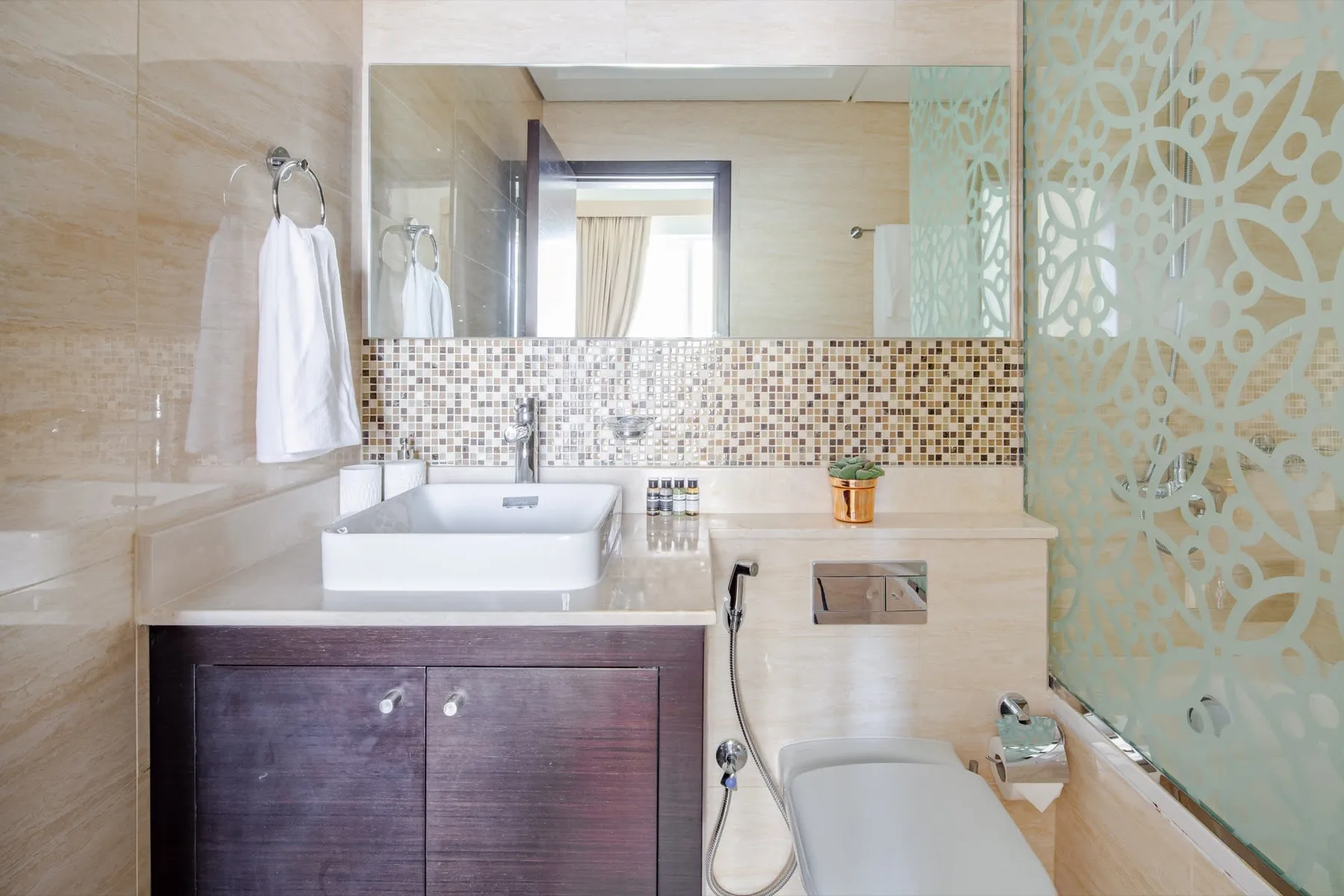 A bathroom with a sink, vanity, and patterned glass partition.