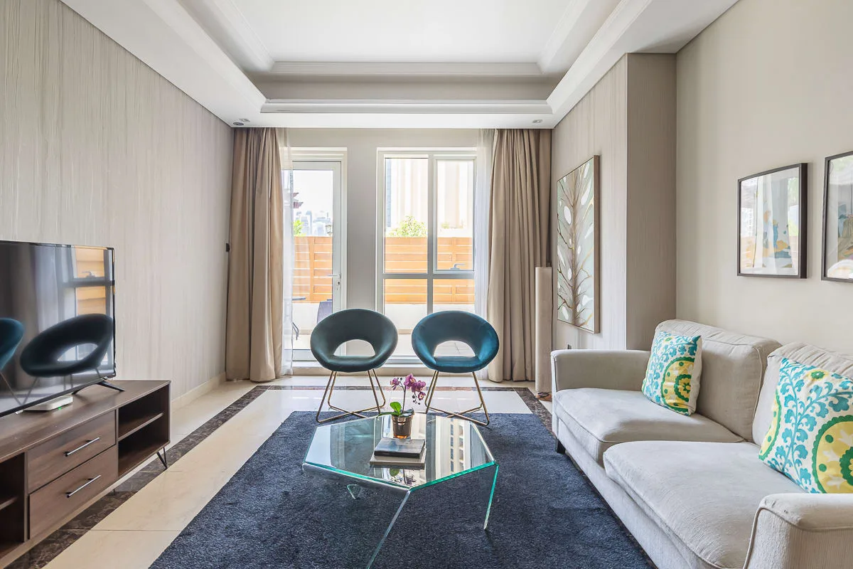 Una sala luminosa con asientos, una mesa de centro y grandes ventanas.