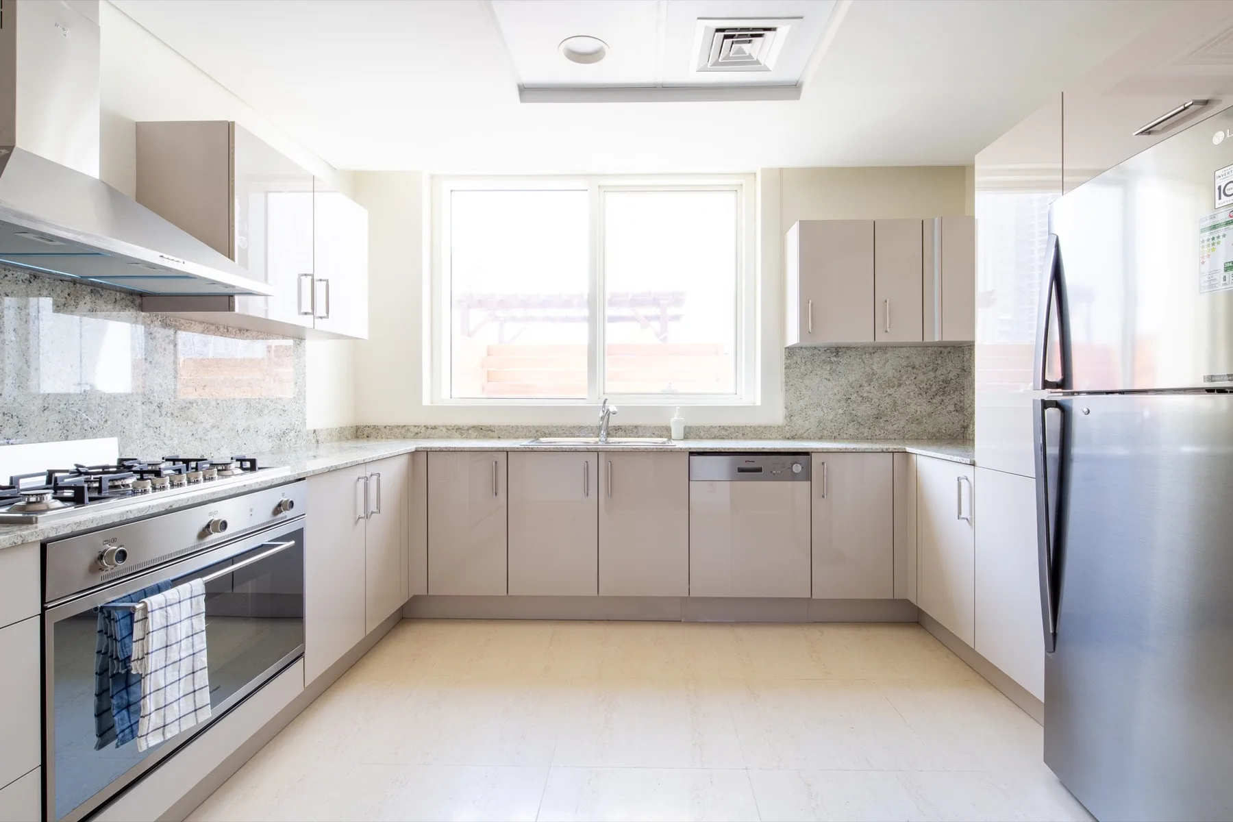 Una cocina luminosa con armarios claros, una encimera y una ventana grande.