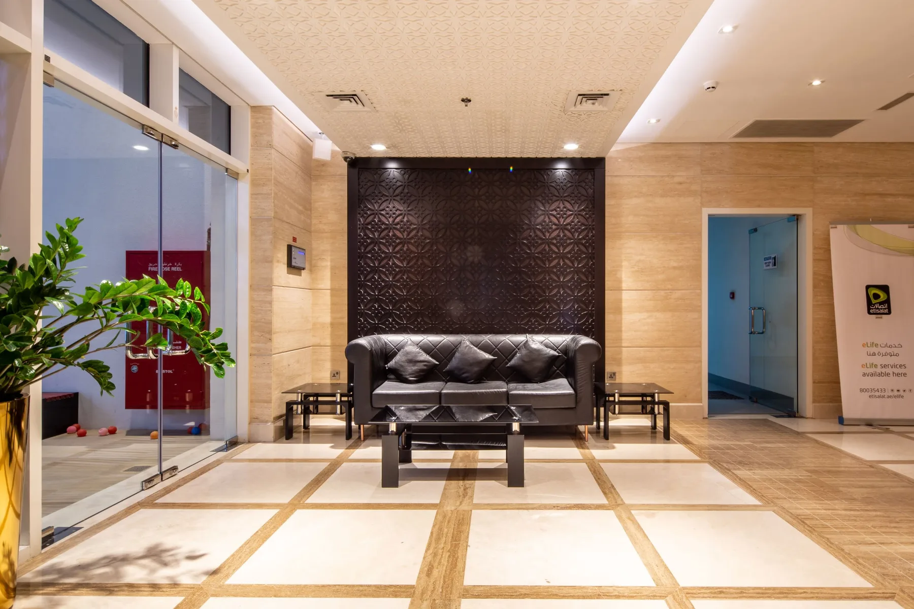 A lobby seating area with dark seating against a textured wall.