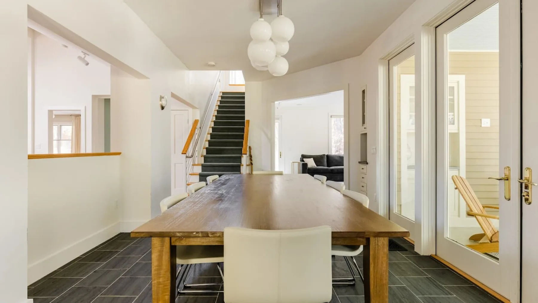 Comedor con una mesa larga de madera y una escalera al fondo.