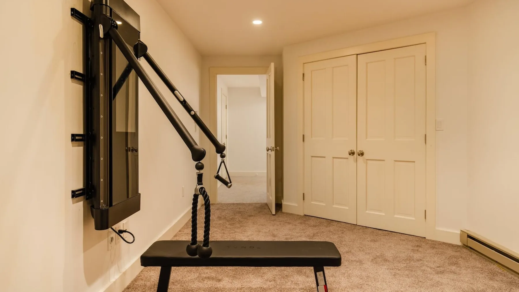Una zona de ejercicio en casa con una máquina de pared y un banco de entrenamiento.