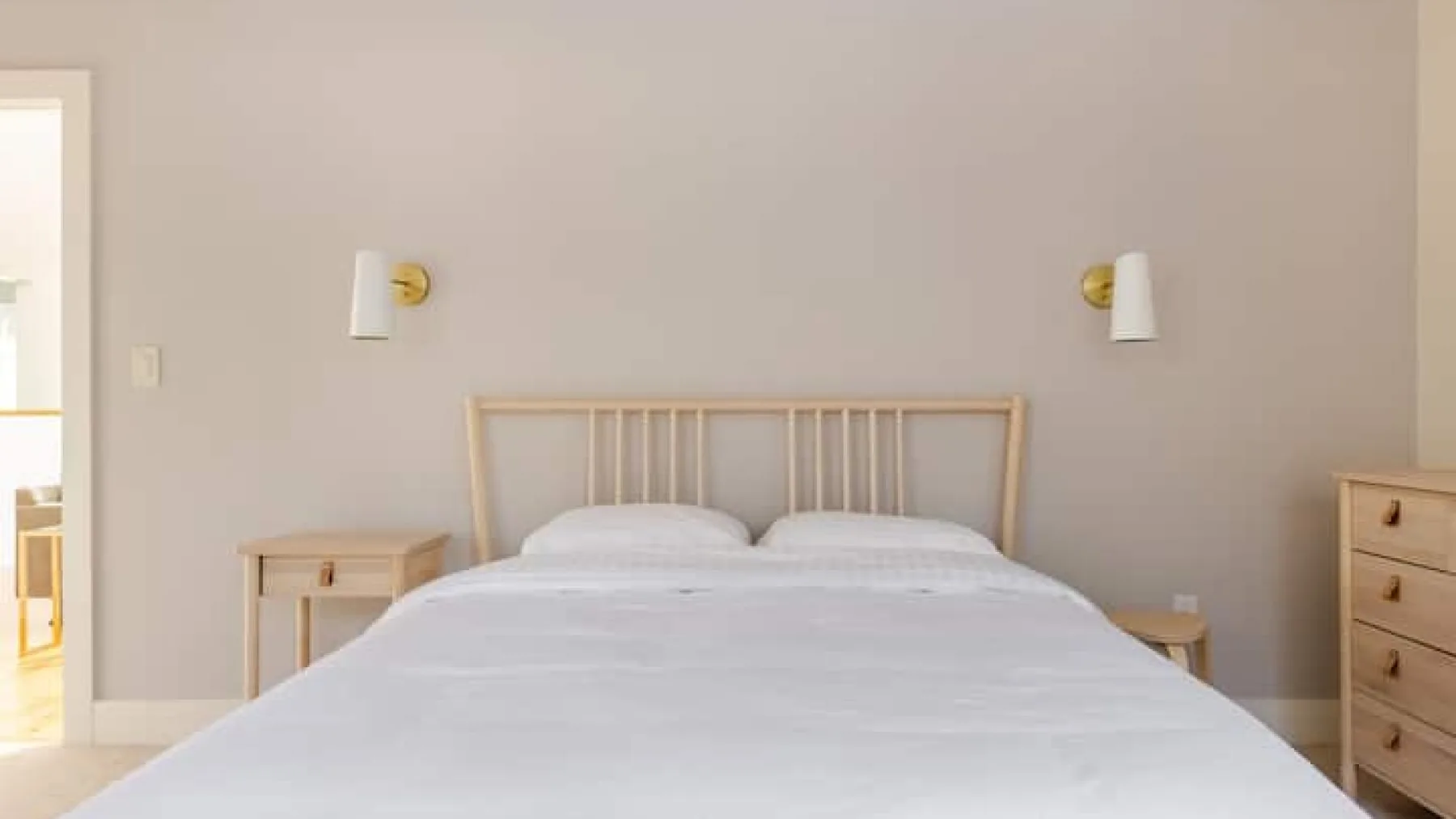 Dormitorio con una cama, mesitas de noche y luces de pared.