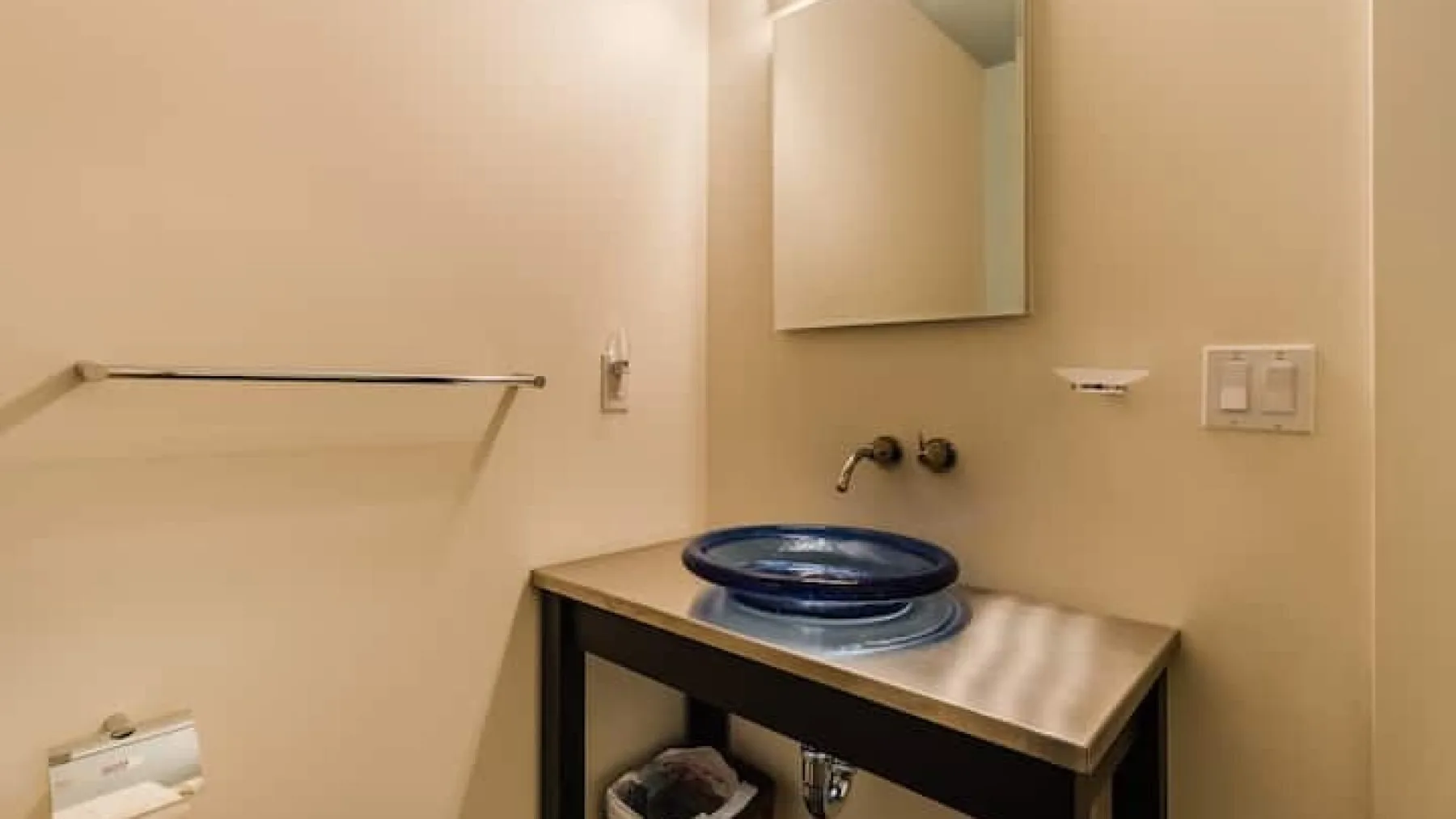 Un tocador de baño con un lavabo azul y un espejo en la pared.