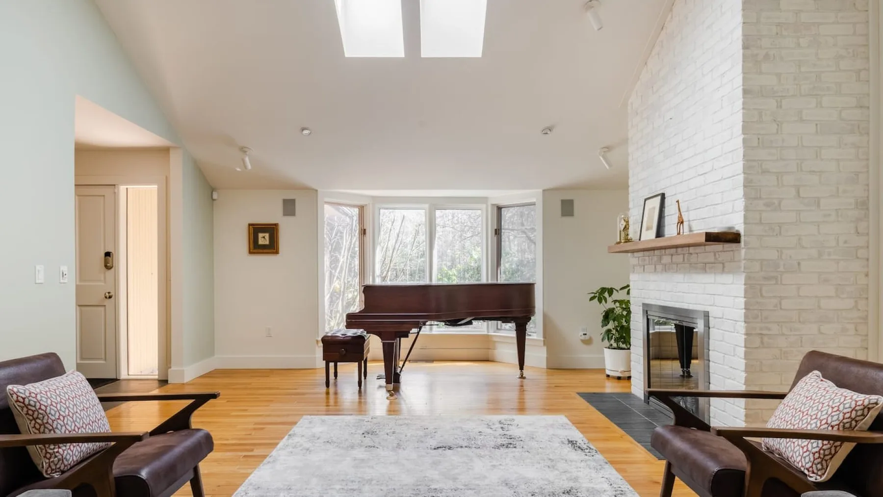 Una luminosa sala de estar cuenta con un piano de cola, asientos y una chimenea.