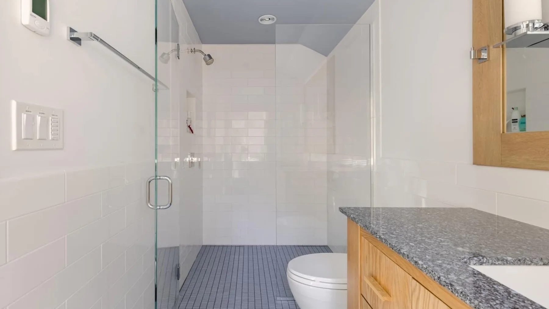 Un baño luminoso con una ducha revestida de azulejos y un tocador.