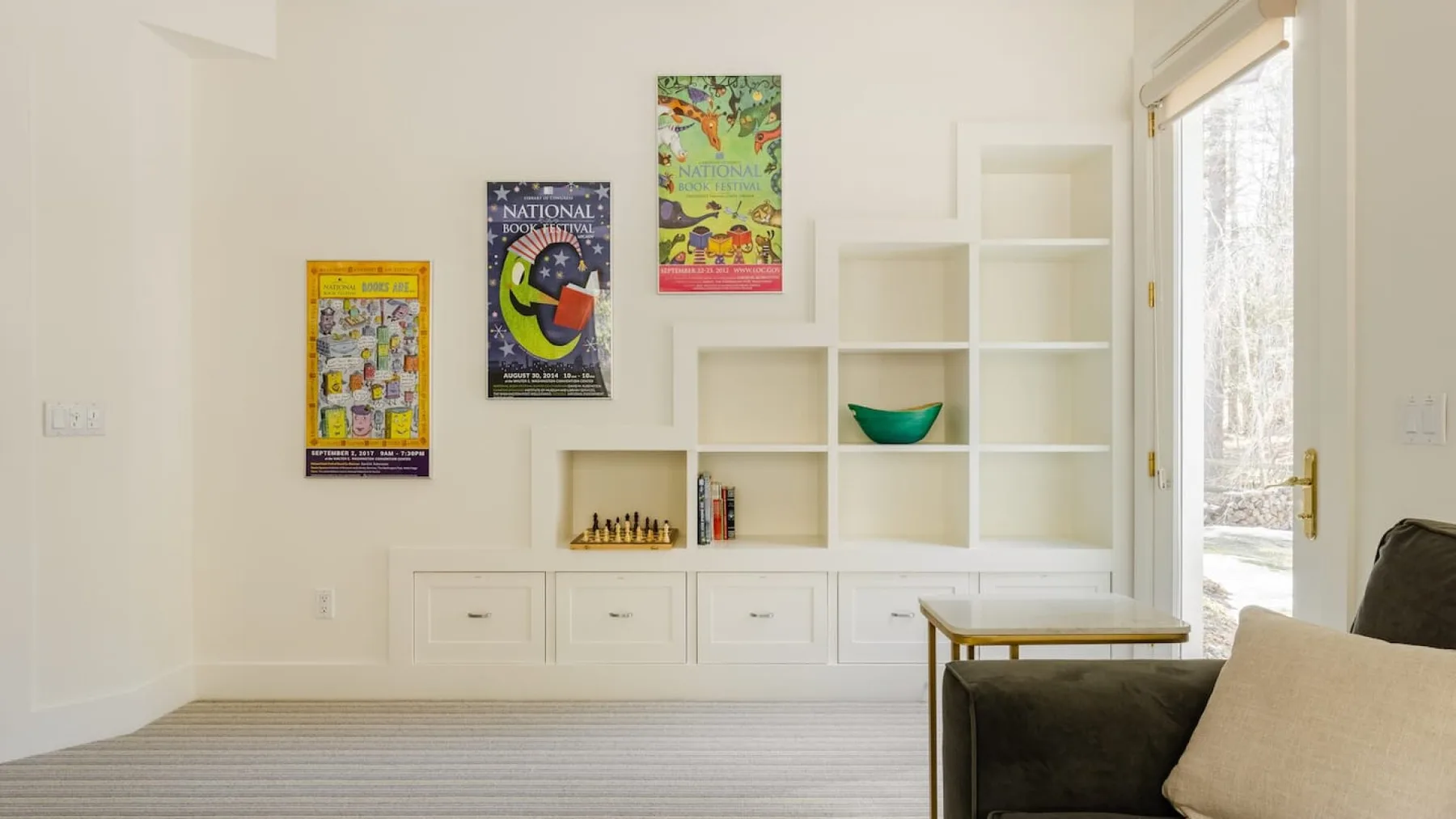 Una luminosa sala de estar con estanterías empotradas, cuadros y una zona para sentarse.