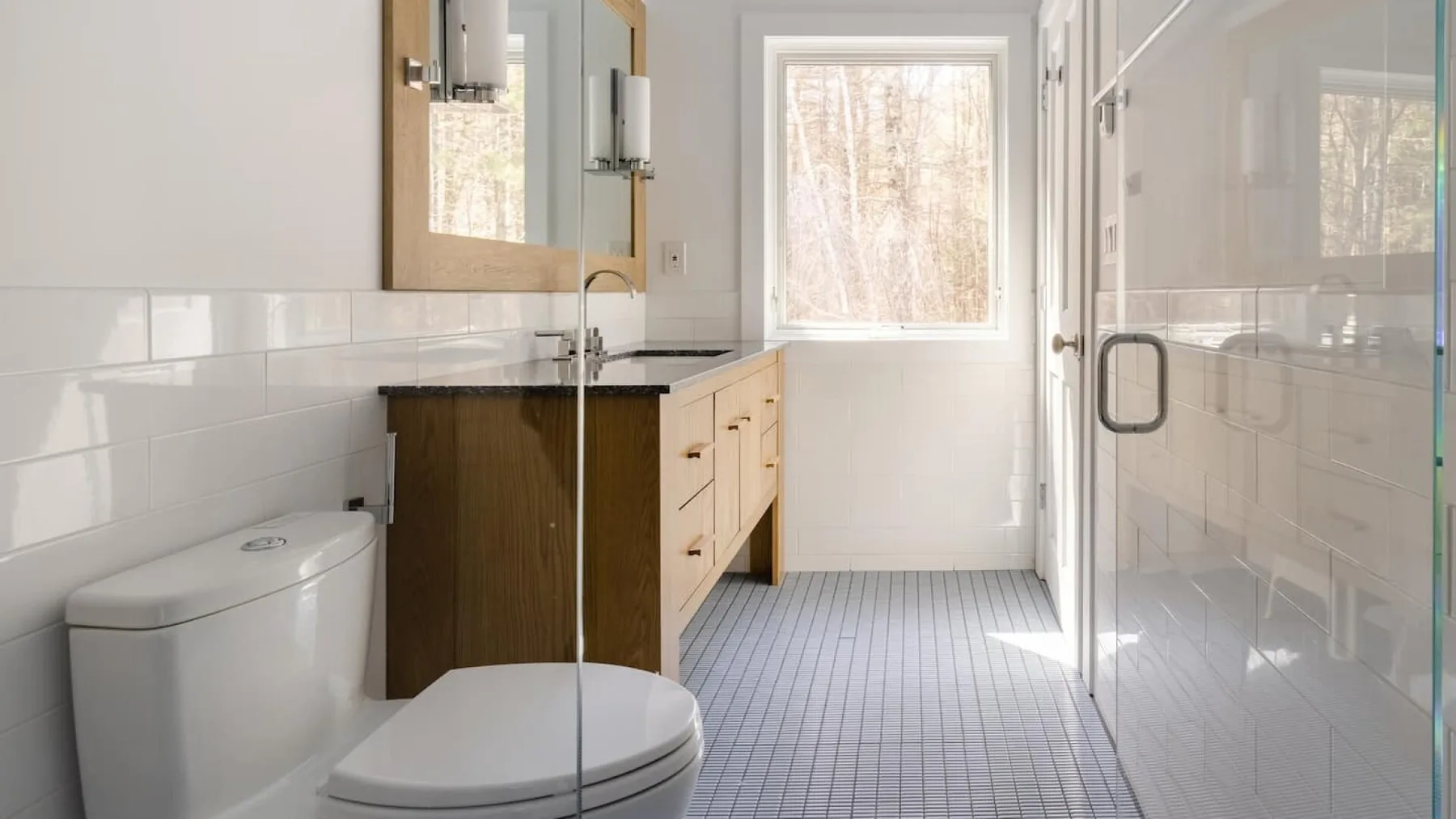 Un baño luminoso con lavabo, inodoro y ducha de vidrio.