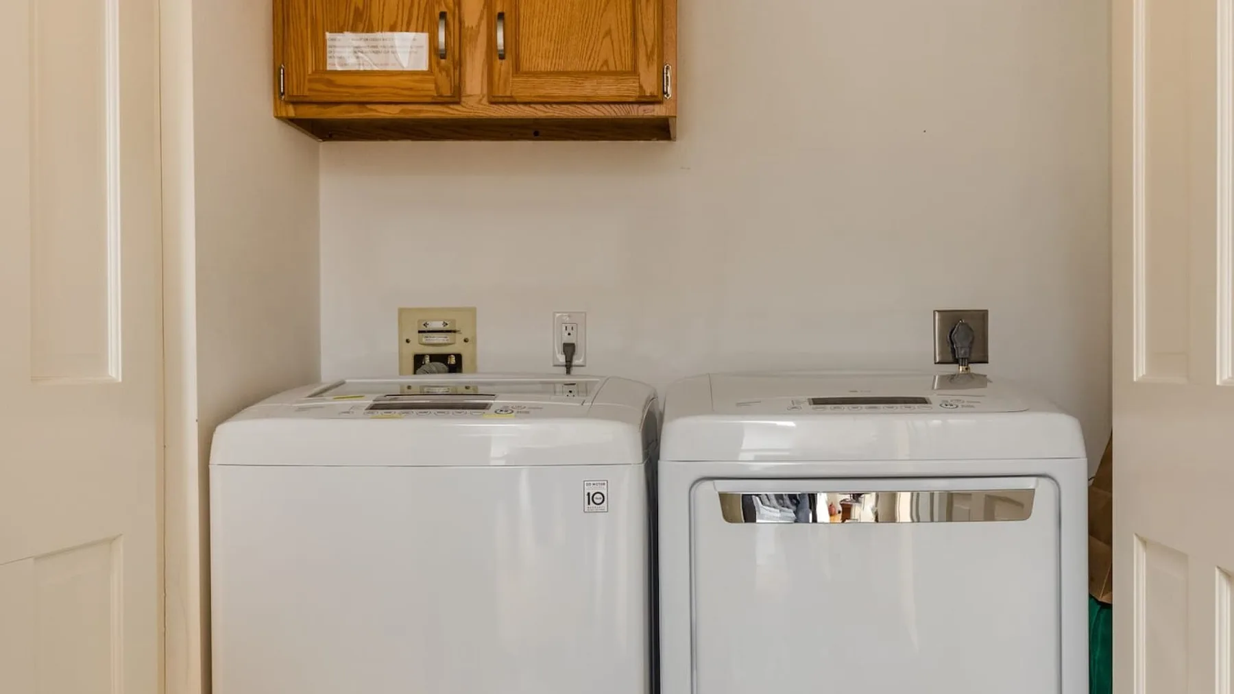 Zona de lavandería con lavadora y secadora bajo armarios de madera.