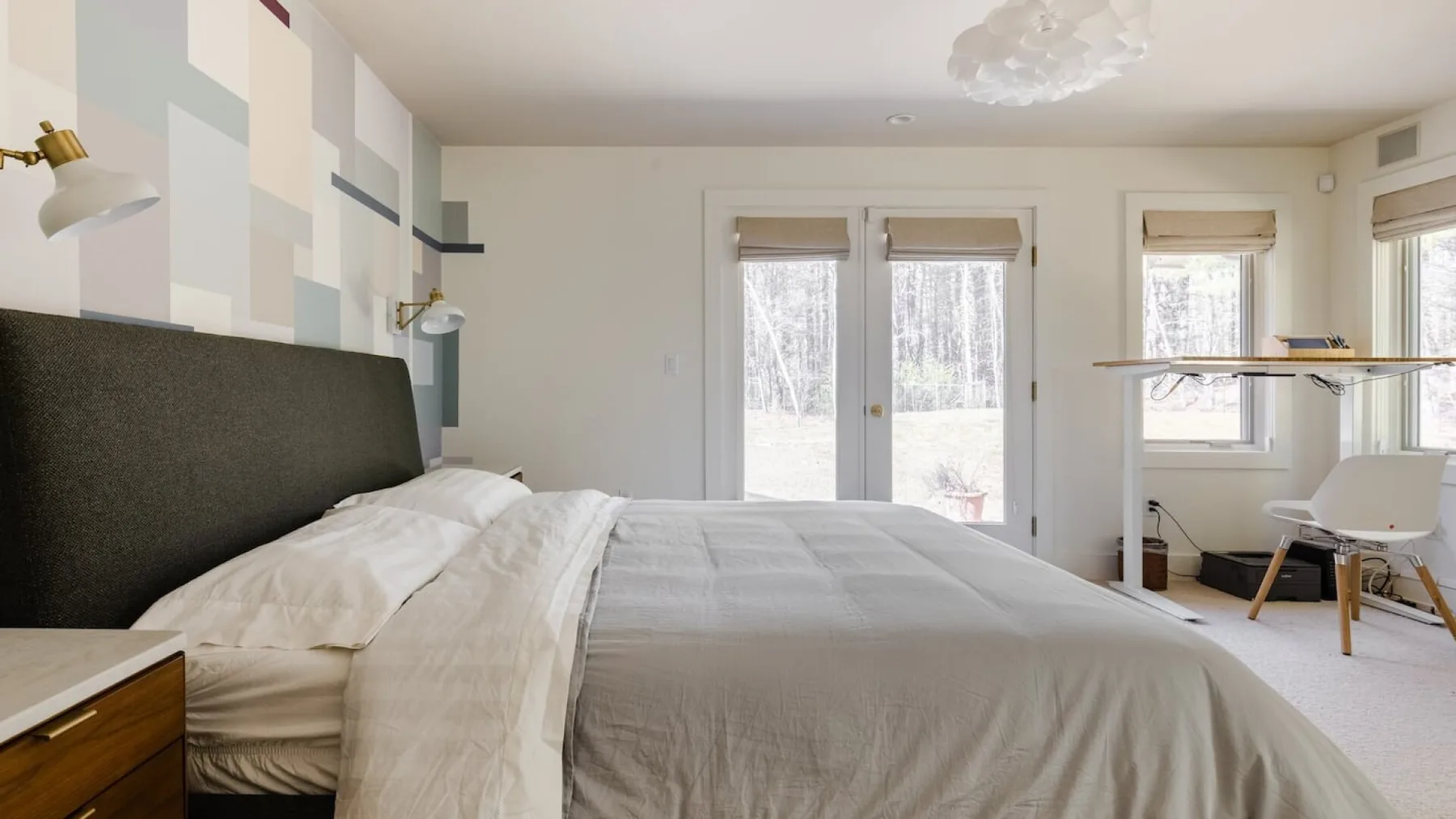 Un dormitorio con una cama grande, una pared estampada y ventanas.