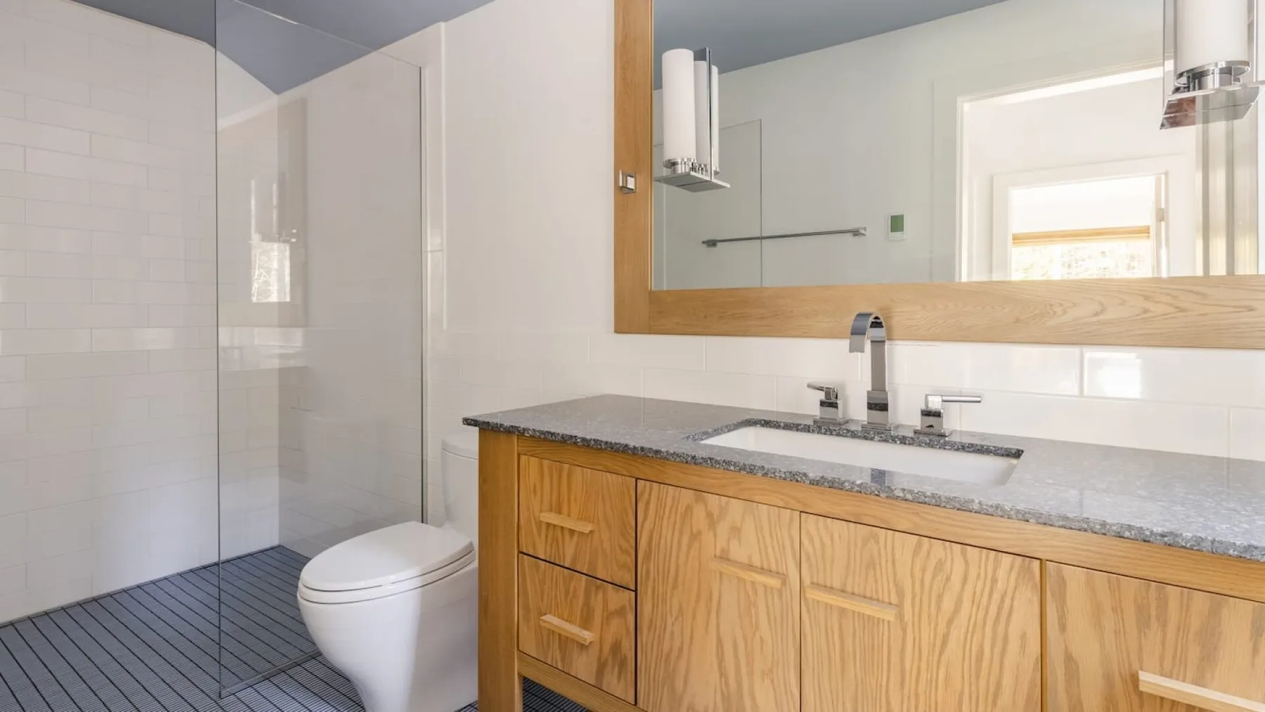 Un baño con tocador, lavabo, inodoro y panel de ducha de vidrio.