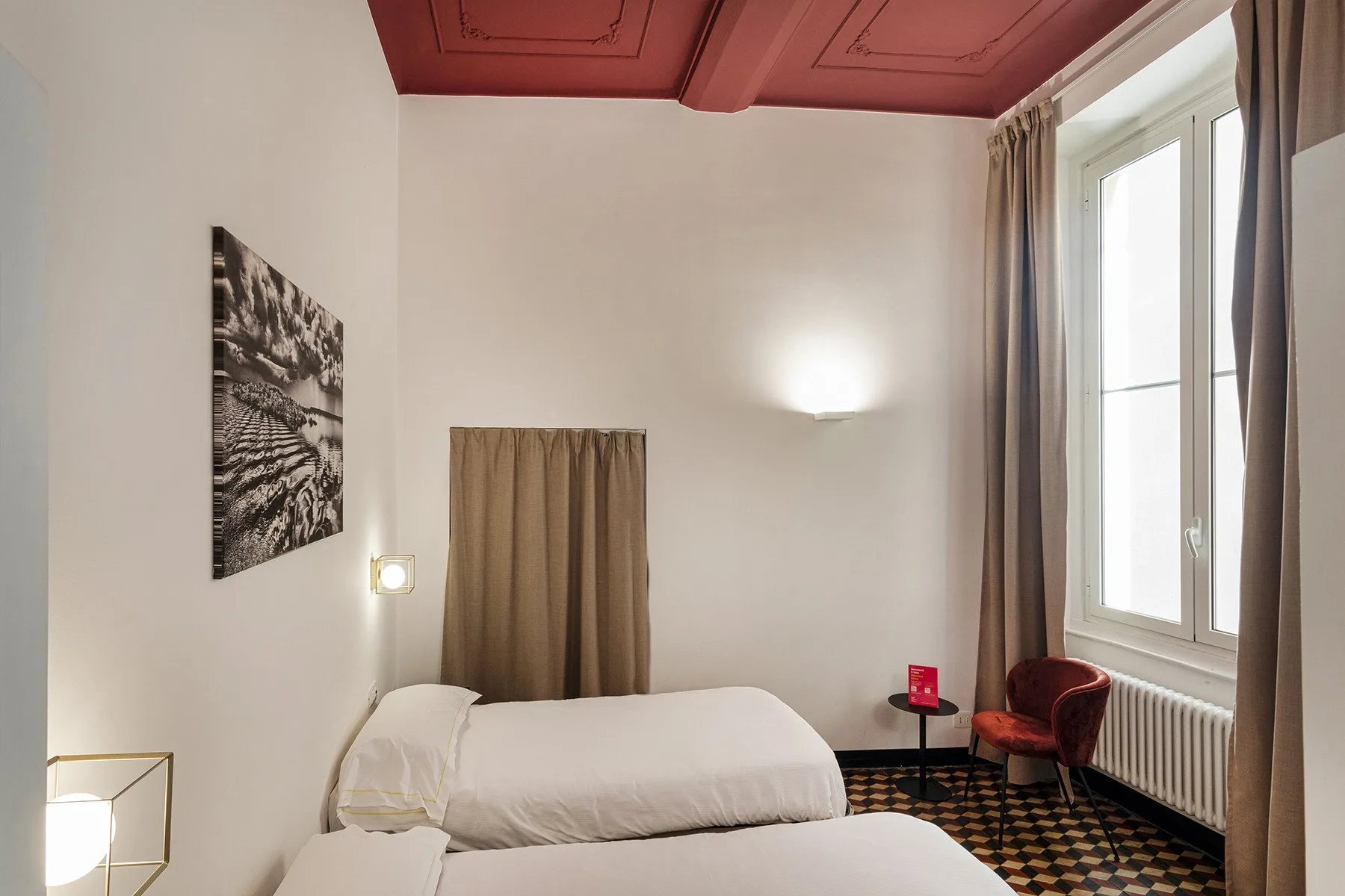 A bedroom with beds, a window, and a red chair.