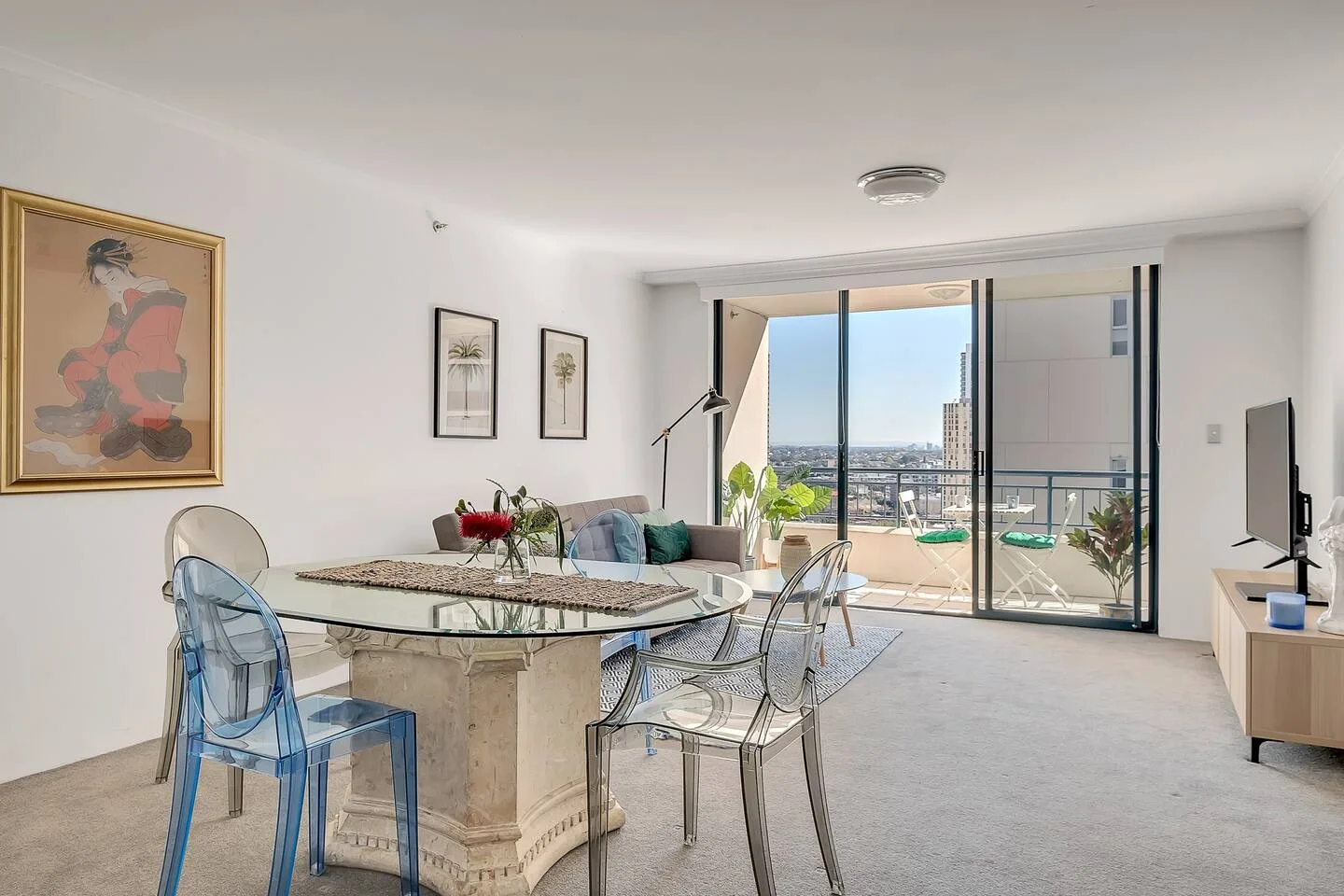 A bright dining area opens onto a balcony with a city view.