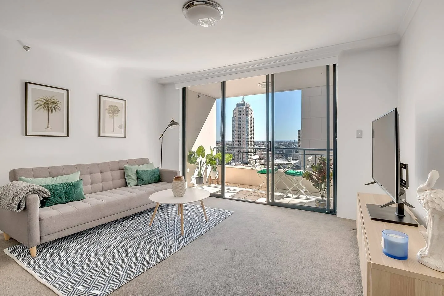 A bright living room opens onto a balcony with city views.