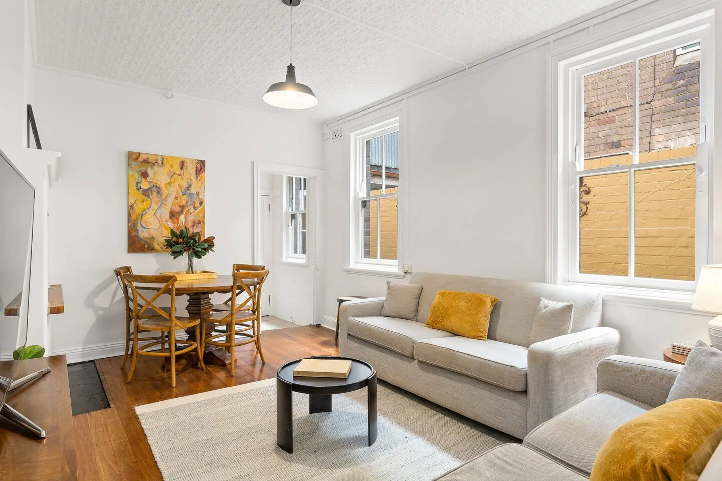 A bright living and dining area features a dining table and light-colored seating.