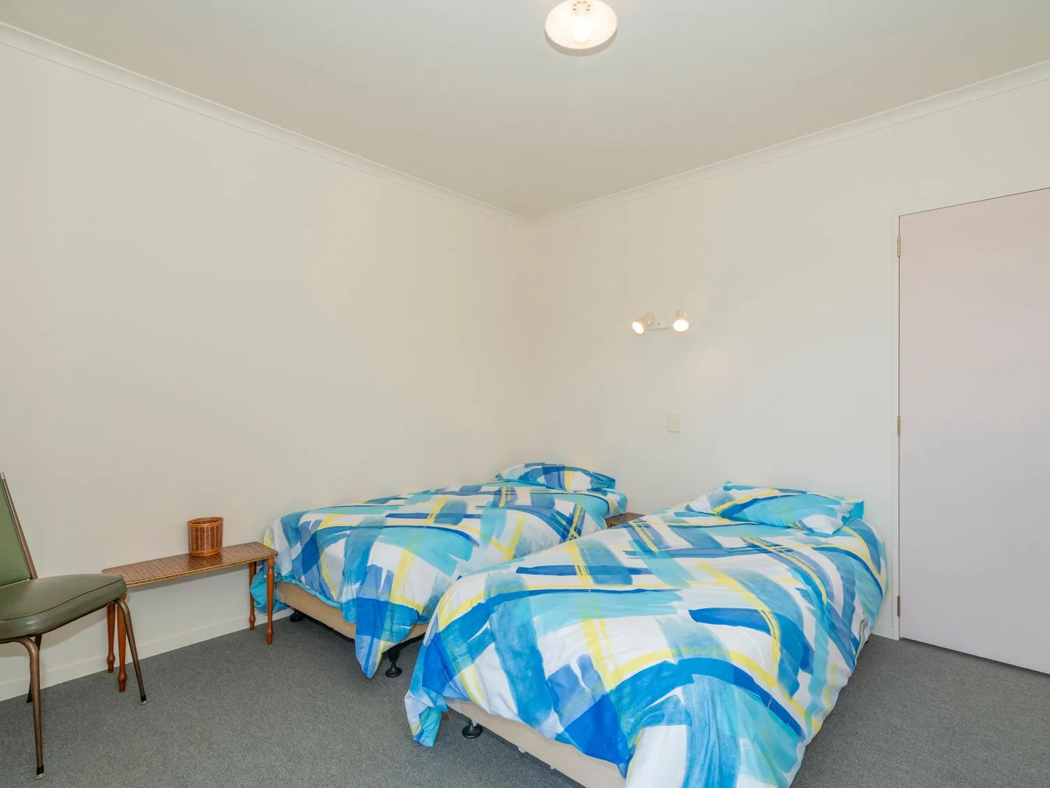 Un dormitorio con dos camas cubiertas con ropa de cama estampada azul, turquesa y amarilla.