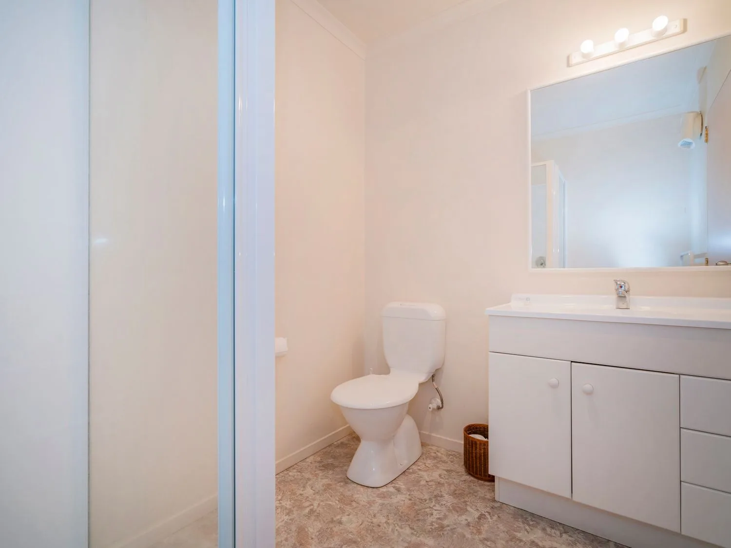 Un baño con inodoro, mueble de lavabo, espejo y ducha.