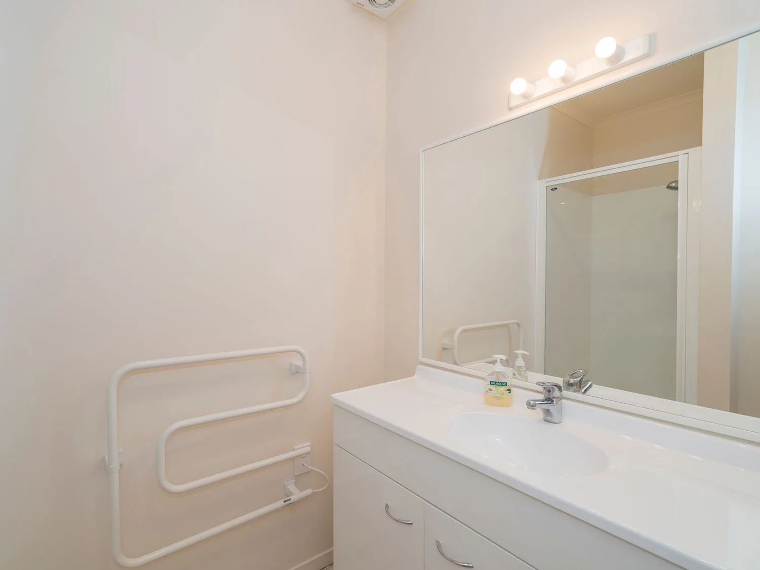 Un lavabo de baño con un espejo encima y un dispensador de jabón sobre la encimera en Pohutukawa on Paku - Tairua Holiday Home, en Tairua.