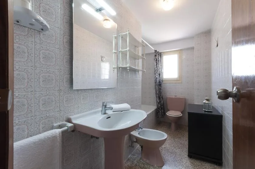 A tiled bathroom with a sink, toilet, and shower area.