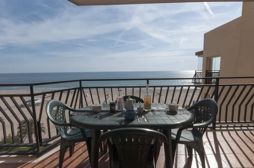 A balcony dining area overlooks the ocean, with a table and chairs.