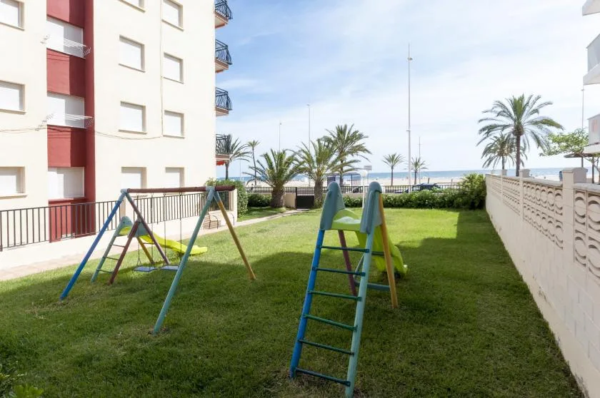 A grassy courtyard with playground swings and palm trees.