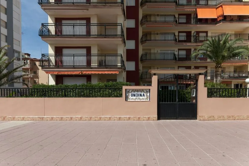 Apartment buildings stand behind a gated entrance and a low wall.